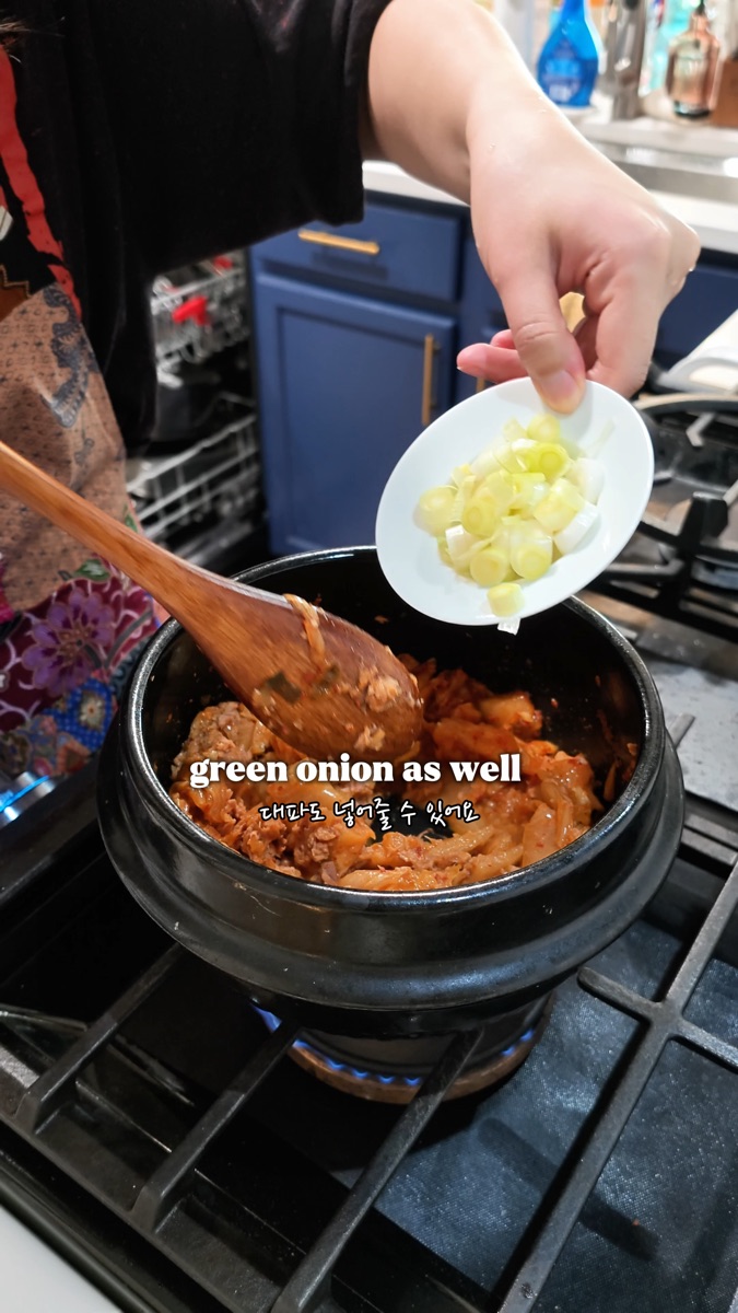 Adding chopped green onion to the pot