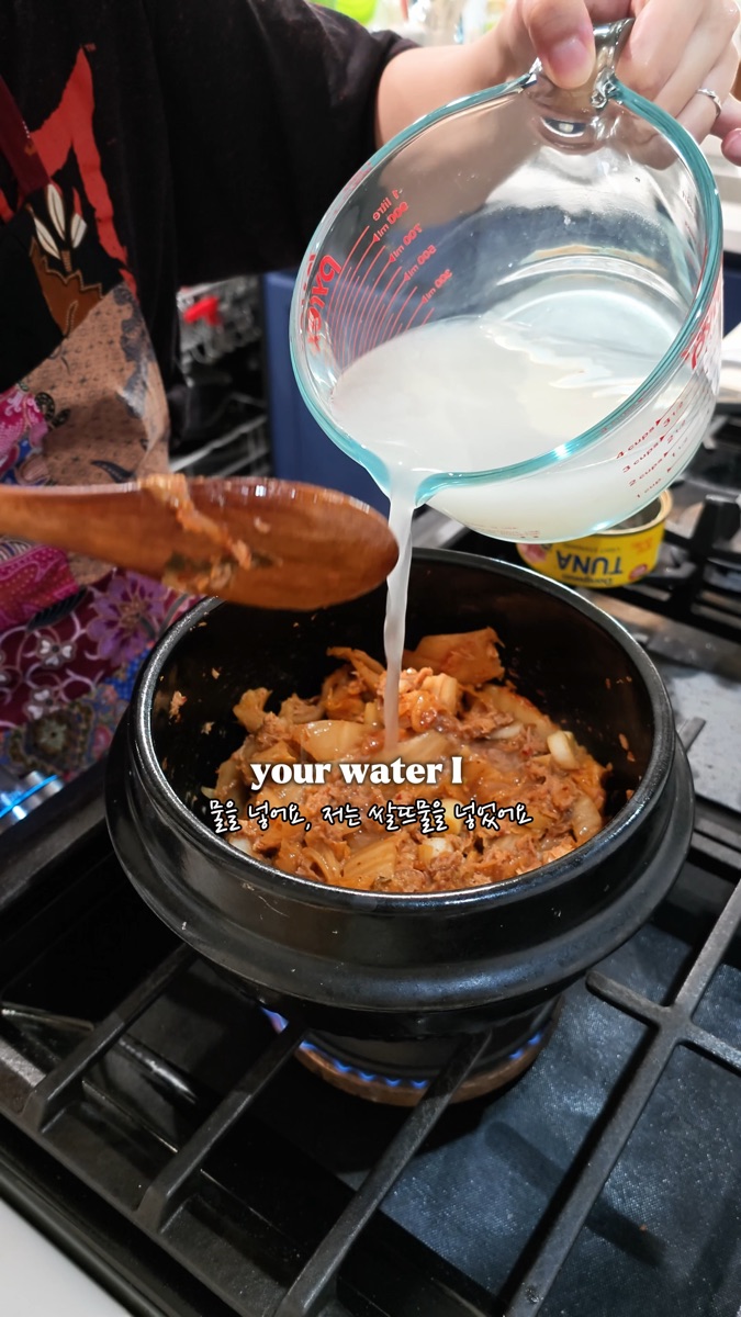 Pouring cloudy rice water into the pot of tuna kimchi stew